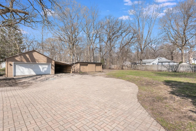 view of yard with a garage, fence, and an outbuilding
