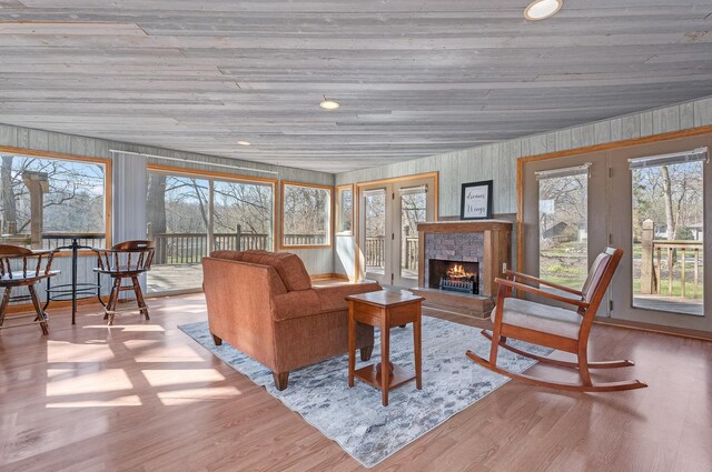 living area featuring a wealth of natural light, a fireplace, wood ceiling, and wood finished floors