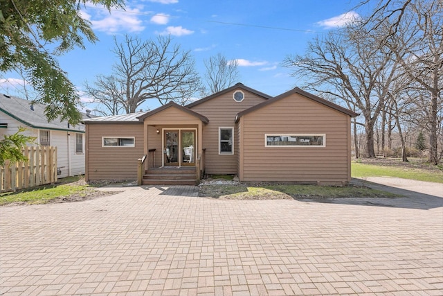 view of front of property featuring metal roof and fence