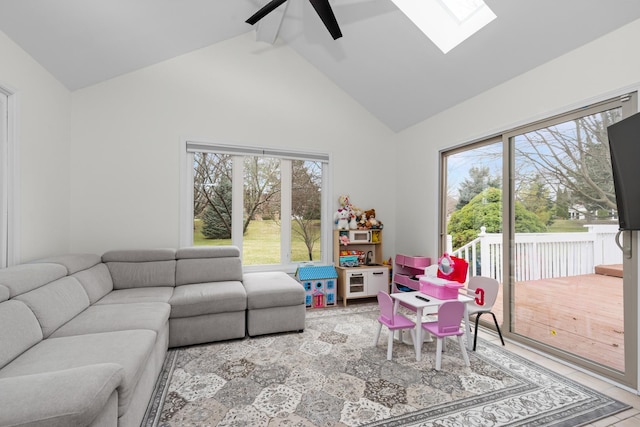 living area featuring high vaulted ceiling, a wealth of natural light, ceiling fan, and a skylight