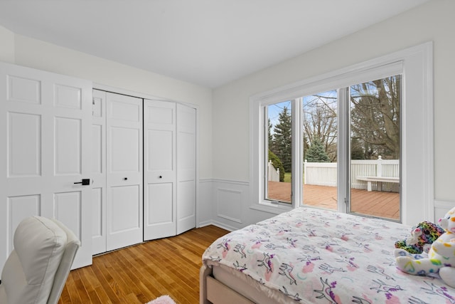 bedroom featuring light wood-style flooring, a closet, access to exterior, and wainscoting