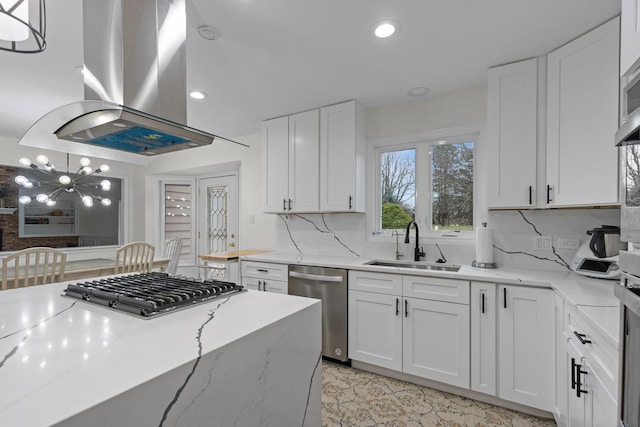 kitchen featuring island exhaust hood, white cabinetry, backsplash, appliances with stainless steel finishes, and a sink