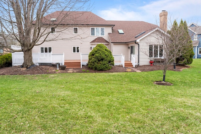 view of front of property with a front yard, a shingled roof, a deck, and a chimney