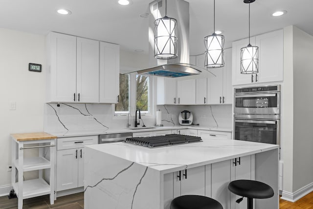 kitchen featuring dark wood-type flooring, wall chimney range hood, white cabinetry, a sink, and stainless steel appliances