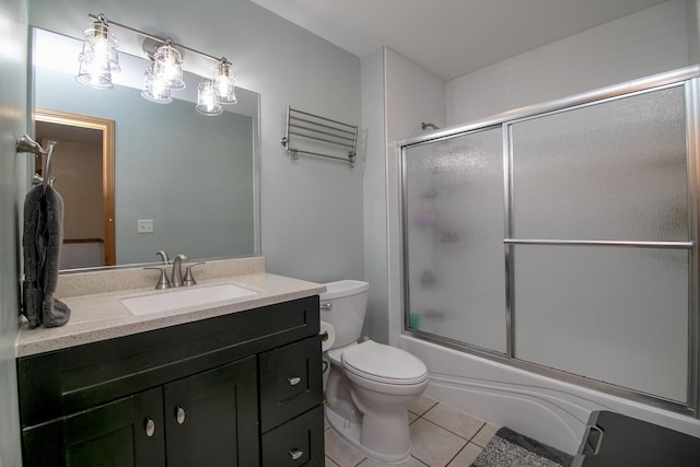 bathroom with toilet, tile patterned floors, vanity, and bath / shower combo with glass door