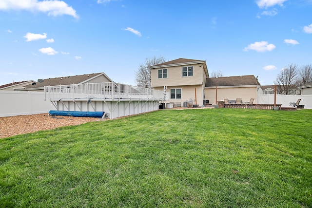 rear view of house featuring a yard, a fenced backyard, and a covered pool
