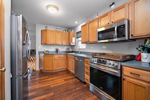 kitchen featuring a sink, dark wood-style flooring, appliances with stainless steel finishes, dark countertops, and recessed lighting
