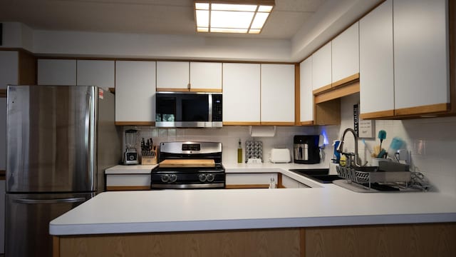 kitchen with a sink, light countertops, tasteful backsplash, and stainless steel appliances