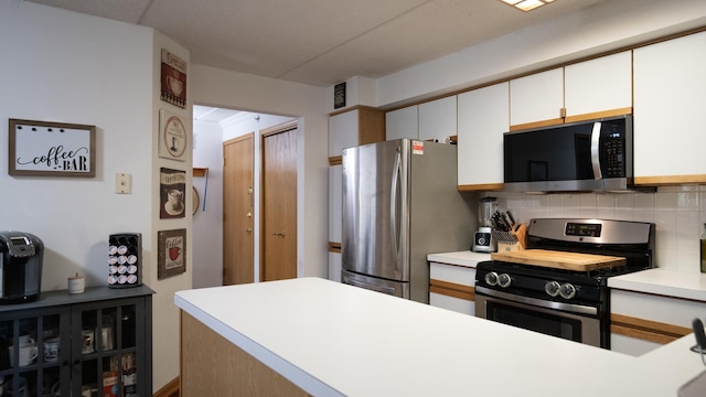 kitchen featuring light countertops, stainless steel appliances, white cabinetry, and backsplash