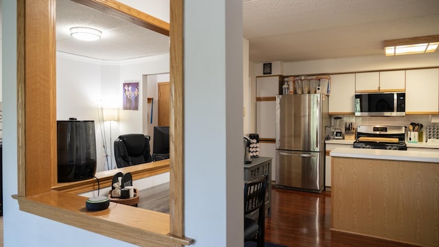 kitchen featuring appliances with stainless steel finishes, light countertops, a textured ceiling, backsplash, and dark wood-style floors