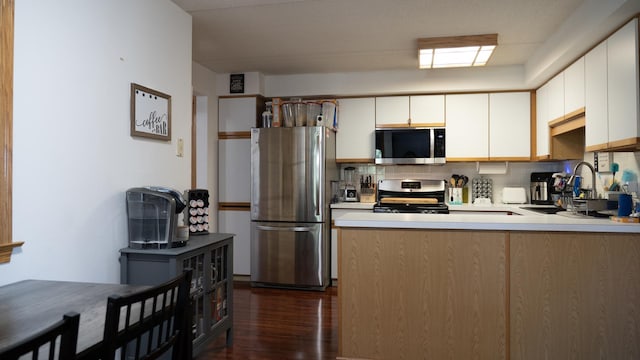 kitchen featuring white cabinets, dark wood-style flooring, appliances with stainless steel finishes, and decorative backsplash