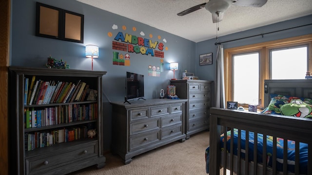carpeted bedroom featuring a ceiling fan and a textured ceiling