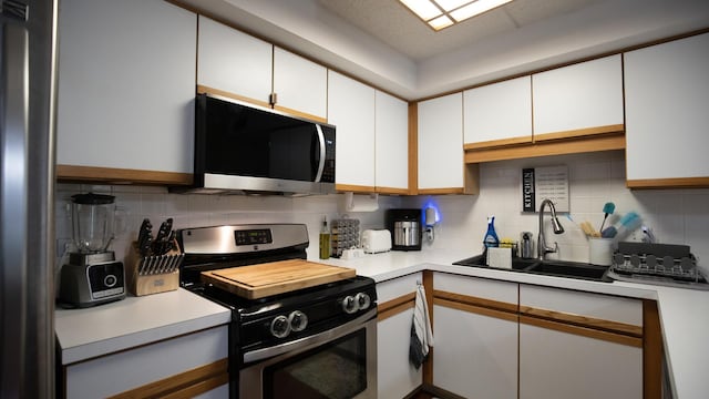 kitchen featuring light countertops, appliances with stainless steel finishes, a sink, and tasteful backsplash