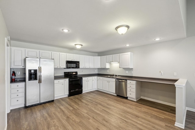 kitchen featuring white cabinets, light wood-style flooring, dark countertops, baseboards, and black appliances