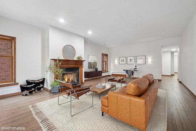 living area with wood-type flooring, baseboards, recessed lighting, and a glass covered fireplace