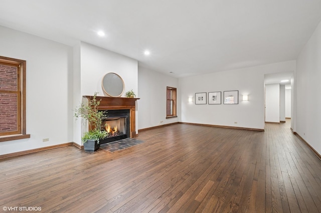 unfurnished living room featuring wood-type flooring, a fireplace with flush hearth, baseboards, and recessed lighting