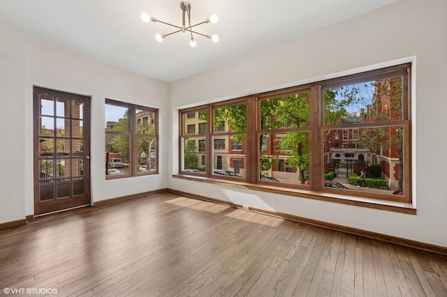 unfurnished room featuring a chandelier, baseboards, and plenty of natural light