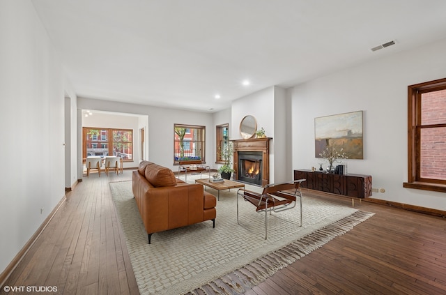 living area with hardwood / wood-style flooring, a lit fireplace, recessed lighting, and baseboards