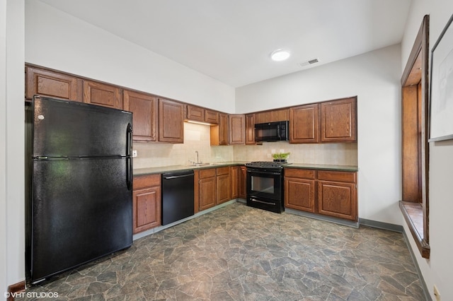 kitchen with black appliances, dark stone finish flooring, decorative backsplash, and brown cabinetry