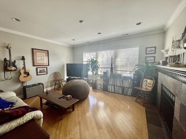 living area featuring a tiled fireplace, visible vents, ornamental molding, and wood-type flooring