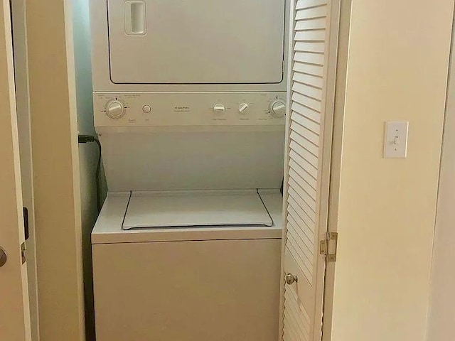 clothes washing area with stacked washer / dryer and laundry area