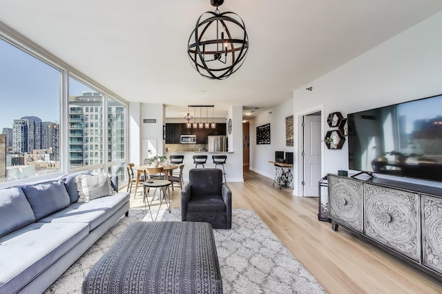 living room with light wood-style floors, a view of city, and a notable chandelier