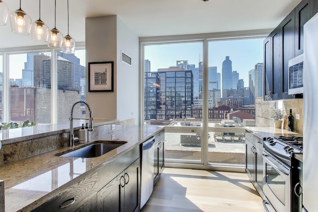 kitchen featuring visible vents, light stone countertops, a city view, a sink, and appliances with stainless steel finishes