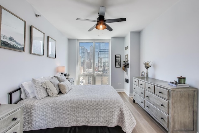 bedroom featuring baseboards, ceiling fan, and light wood-style flooring