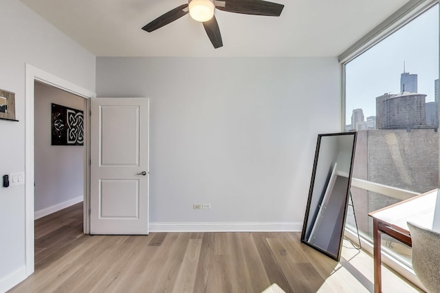 spare room featuring baseboards, a ceiling fan, and wood finished floors