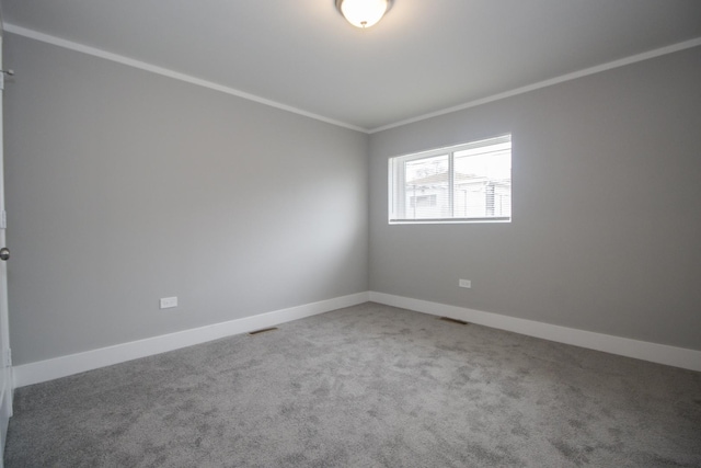 carpeted spare room with visible vents, baseboards, and crown molding