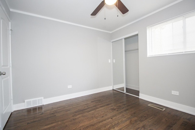 unfurnished bedroom featuring a closet, wood finished floors, ornamental molding, and visible vents