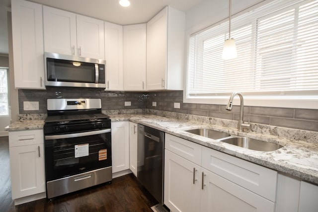 kitchen featuring appliances with stainless steel finishes, a sink, white cabinets, and a wealth of natural light