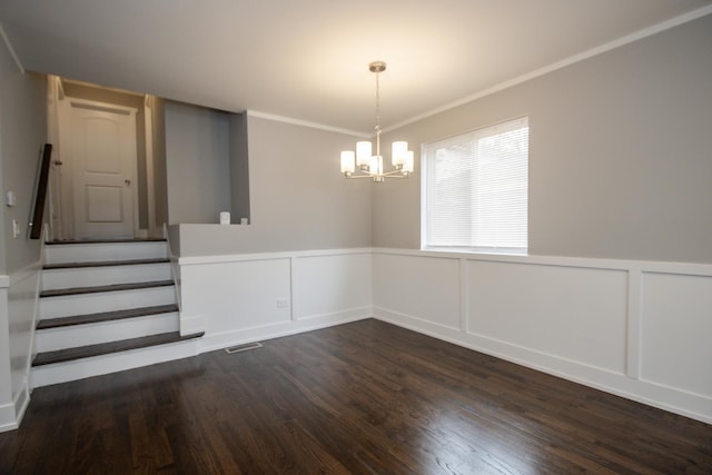 unfurnished dining area featuring stairway, dark wood-type flooring, a notable chandelier, and a wainscoted wall
