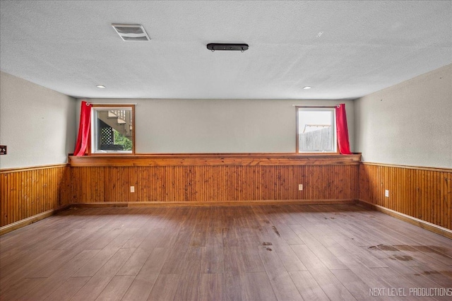 317 Plymouth Ct, Sycamore, IL 60178 - empty room with wainscoting, hardwood / wood-style floors, a textured ceiling, and wood walls
