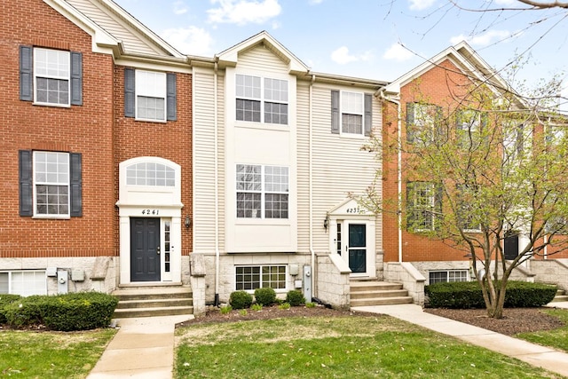 multi unit property featuring a front lawn, entry steps, and brick siding