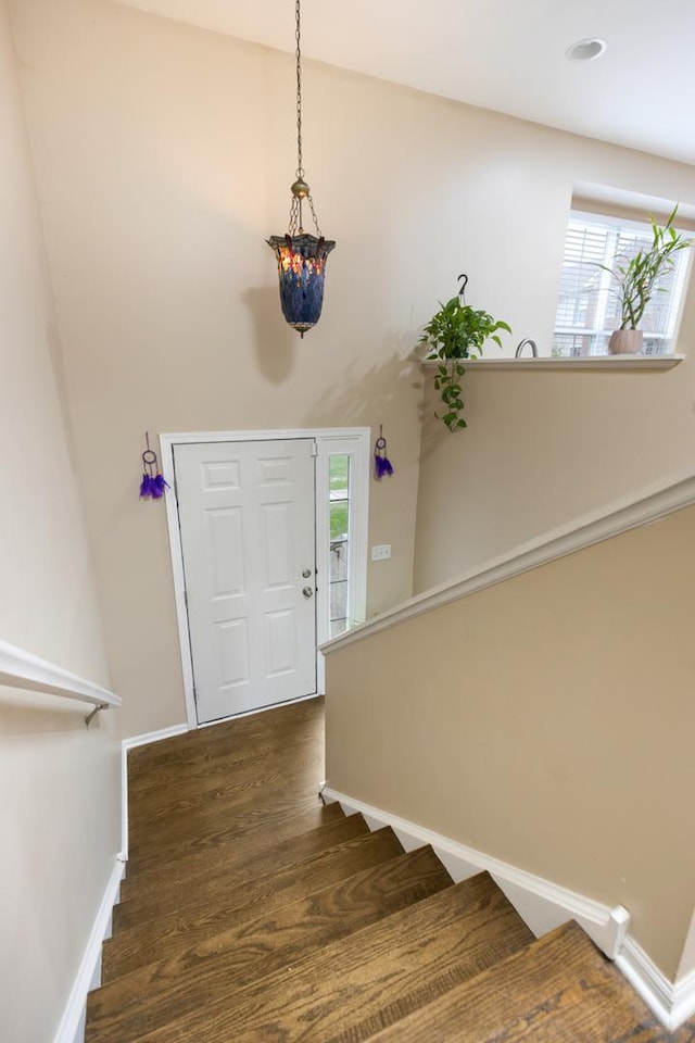 entrance foyer featuring dark wood-type flooring, a chandelier, baseboards, and stairs