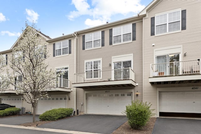 townhome / multi-family property with driveway, an attached garage, and central AC unit