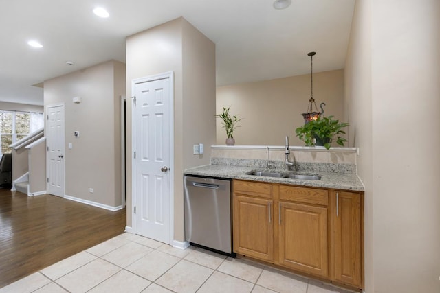 kitchen featuring light stone counters, stainless steel dishwasher, a sink, baseboards, and light tile patterned flooring