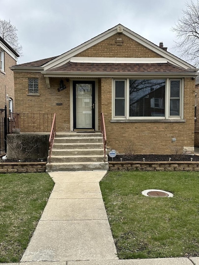 8817 S Constance Ave, Chicago, IL 60617 - view of front facade with a shingled roof, a front yard, and brick siding