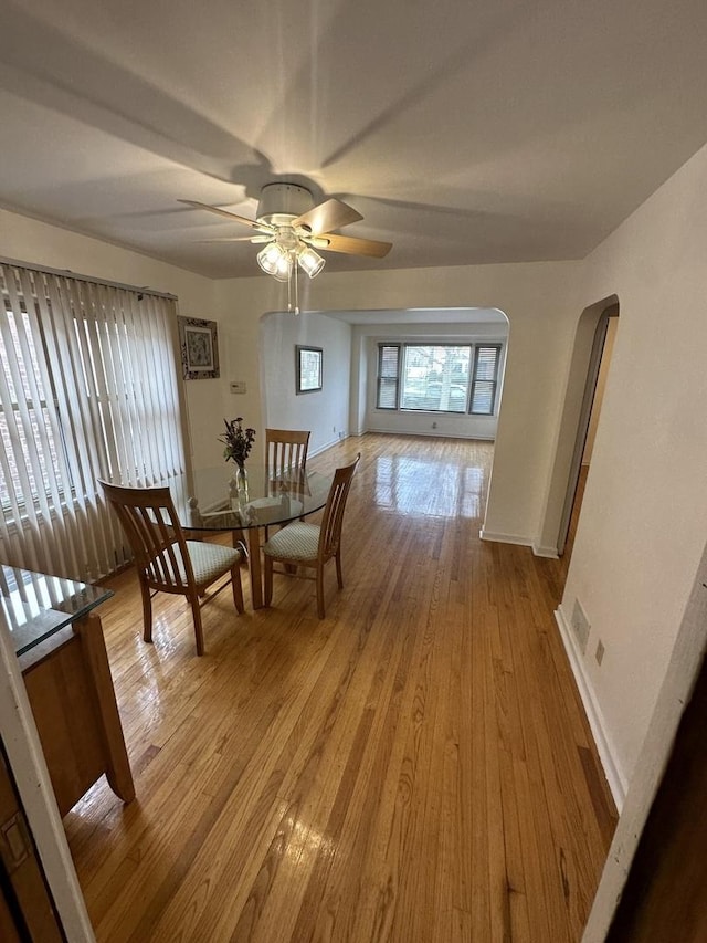 8817 S Constance Ave, Chicago, IL 60617 - dining space with arched walkways, ceiling fan, baseboards, and light wood-type flooring