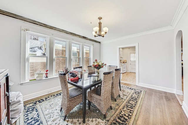 dining area featuring arched walkways, crown molding, a notable chandelier, and baseboards