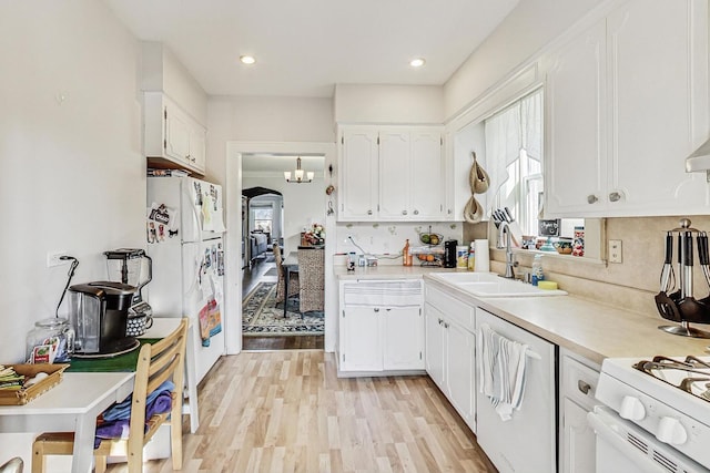 kitchen with a sink, a wealth of natural light, white appliances, and white cabinets