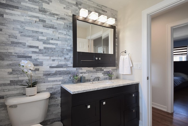 bathroom featuring backsplash, toilet, wood finished floors, and vanity