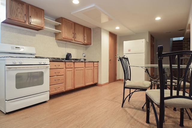 kitchen featuring dark countertops, tasteful backsplash, light wood-style floors, recessed lighting, and white appliances