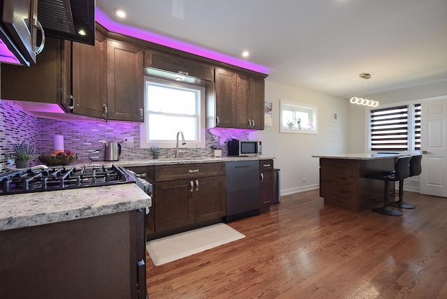 kitchen with dishwashing machine, tasteful backsplash, stainless steel microwave, and a sink