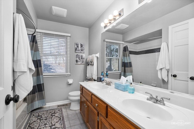 bathroom with toilet, tile patterned floors, double vanity, and a sink