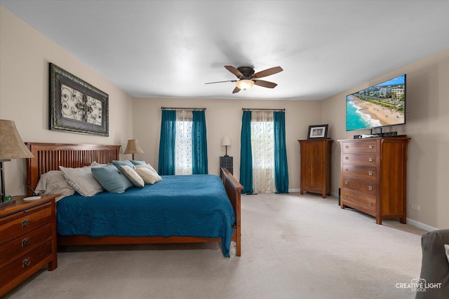 bedroom featuring light carpet, baseboards, and a ceiling fan