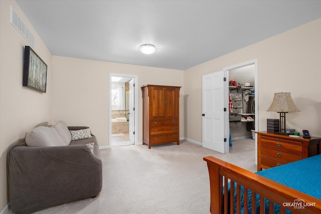 bedroom featuring a closet, visible vents, light carpet, a walk in closet, and baseboards