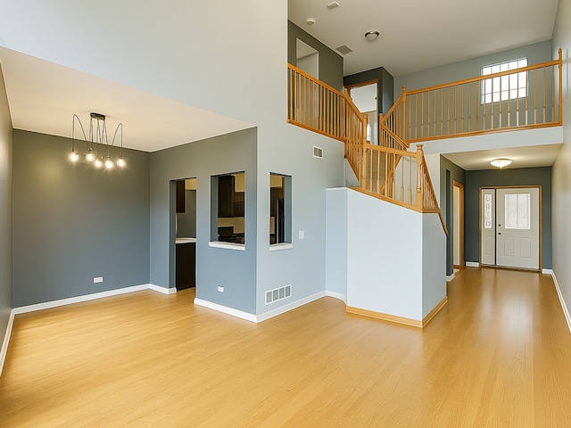 unfurnished living room with a healthy amount of sunlight, visible vents, and wood finished floors