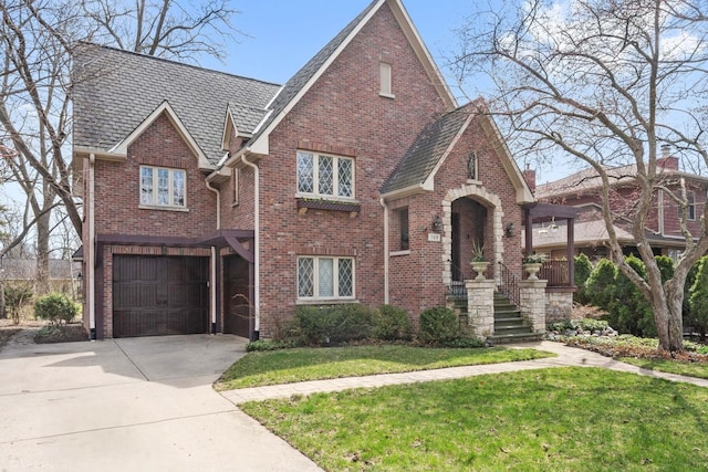 view of front facade with a front lawn, driveway, brick siding, and a garage